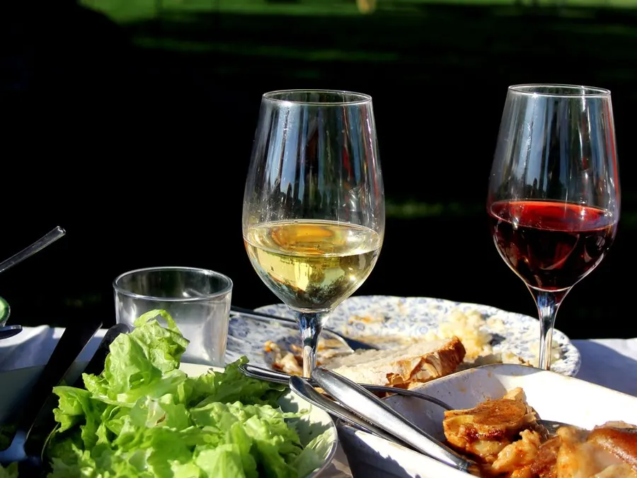 Mesa con copas de vino, ensalada y platos para compartir